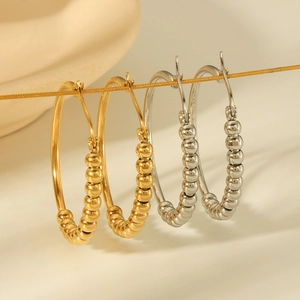 Detailed close-up of gold and silver beaded titanium steel hoop earrings on a gold chain