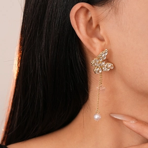 Macro shot of gold butterfly earrings with sparkling crystals and elegant pearl tassels