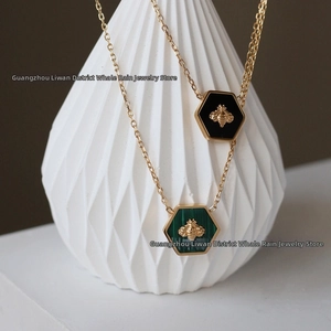 Detailed close-up of honeycomb bee pendant necklaces with green and black enamel inlay