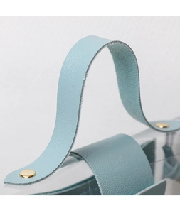 Detail of light blue lychee pattern leather handle with gold rivets and clear PVC