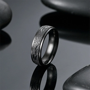 Detail of black frosted titanium steel ring with elegant carved patterns on a zen background