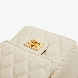 Detail of cream quilted PU leather with a gold-tone rectangular swivel lock closure