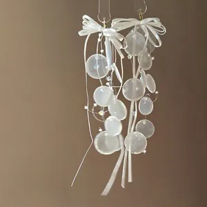 Macro shot of white ribbon bow earrings with translucent sequin fringes and beads