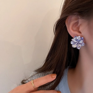 Close-up of elegant purple flower earrings with sparkling accents worn by a model