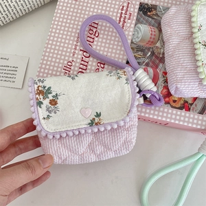 Detailed view of floral pattern fabric and white pom-pom trim on a purple storage pouch