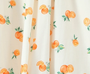 Detailed close-up of summer orange print on soft cotton-linen fabric with lace trim