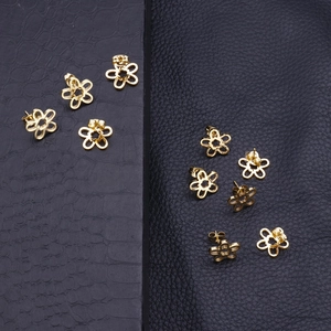 Elegante goldene Sonnenblumen-Ohrstecker im minimalistischen Design auf schwarzem Leder