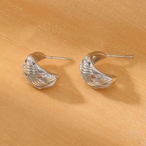 Macro detail of silver intertwined geometric earrings on silk background