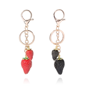 Detail of red and black strawberry keychains with golden clasps and lifelike texture
