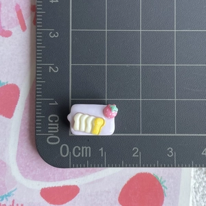 Miniature resin strawberry cream cake charm on a CM scale cutting mat for size