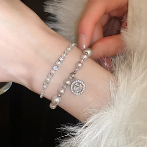 Close-up of double-layer silver bracelet with zircon accents and white pearls on wrist