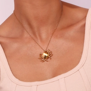 Close-up of a 18K gold plated crab pendant necklace worn by a model in detail