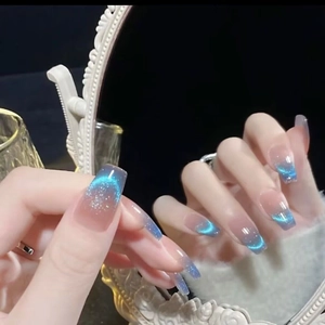 Macro detail of blue cat eye press-on nails with silver glitter and icy nude gradient