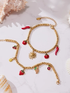 Detail of beaded bracelet with strawberry, cherry, and pineapple charms on marble surface