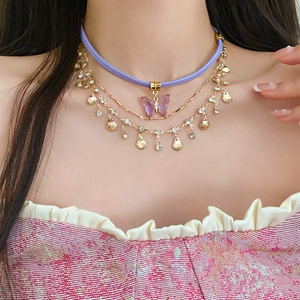 Detail of multi-layer butterfly choker with purple charm and golden shell pendant on neck