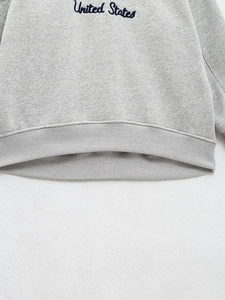 Détail du bord-côte du sweat gris avec broderie United States en gros plan