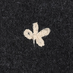 Black cardigan with hand-woven white flower detail and textured wool-like fabric