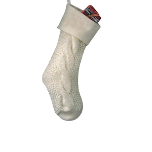Close-up of cream knit Christmas stocking with classic cable stitch texture and gift boxes