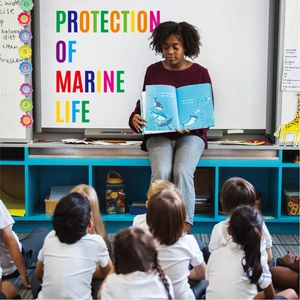Detailed view of teacher reading marine life protection educational book in classroom
