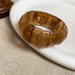 Close-up of a vintage amber resin elastic bracelet on a ceramic plate background