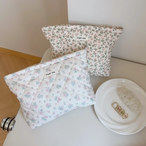 Détail de trousses de maquillage matelassées en coton avec motif floral rose et étiquette