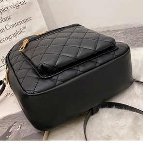Macro side view of black quilted leather mini backpack with golden zipper and thick base