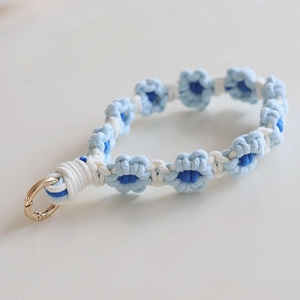 Macro shot of hand-woven blue daisy flower lanyard with a gold spring ring clasp