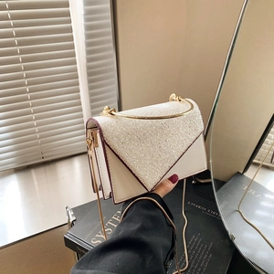 Detailansicht der weißen Perlglanz-Handtasche mit goldenem Ringgriff und Kettenriemen