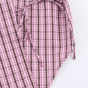 Détail du tissu à carreaux rose et marron avec un lien de serrage fin assorti
