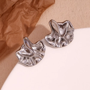 Detail of silver liquid metal petal earrings on a white minimalist display stand