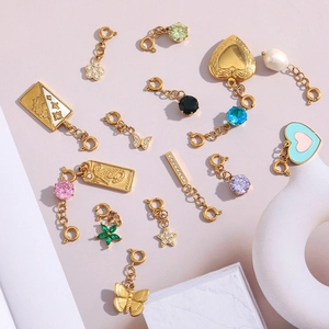 Detail of 18K gold plated charms with heart, butterfly, and enamel accents for jewelry