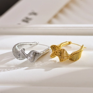Macro detail of twisted spiral wire texture on gold and silver irregular hoop earrings