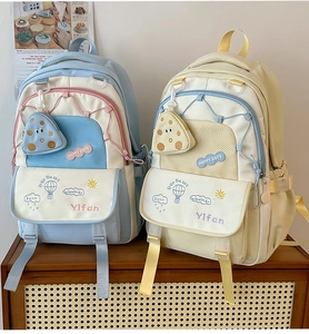 Front detail of blue and yellow large capacity school backpacks on a woven wood shelf