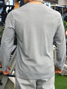 Slim fit men's long sleeve polo with vertical stripes shown from the back in a gym setting
