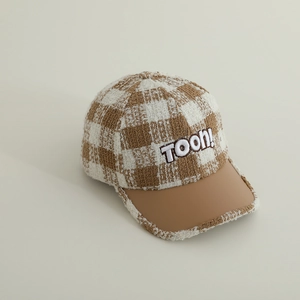 Detail of child baseball cap showing plaid tweed fabric and leather brim with TOON embroidery