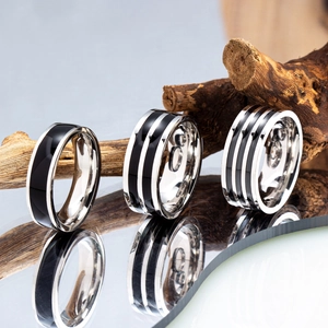 Titanium steel striped rings in black and silver finishes on a reflective surface