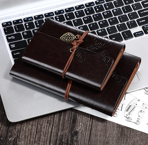 Vintage leather notebook with leaf pendant on a laptop keyboard for office use
