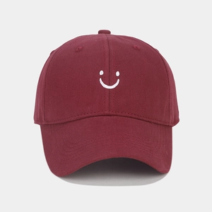 Detailed embroidery of a white smiley face on a burgundy cotton twill baseball cap