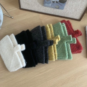 Flat lay of six colorful knitted pouches in white black gray yellow green and red