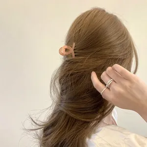Minimalist translucent peach acrylic hair claw clip shown with elegant silver rings