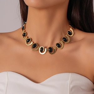 Close-up of vintage gold necklace featuring oval black gemstones on a female model