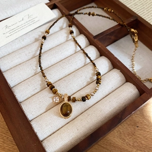 Detail shot of tiger eye stone pendant necklace on a wooden jewelry display tray
