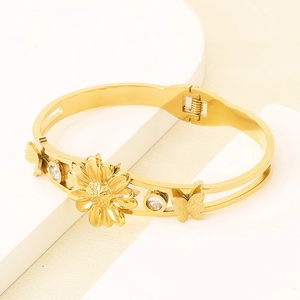 Détail d'un bracelet doré avec marguerite et papillon orné de pierres de zircon scintillantes