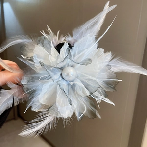 Detailed close-up of feather flower hair clip with white pearl center and blue gradient petals