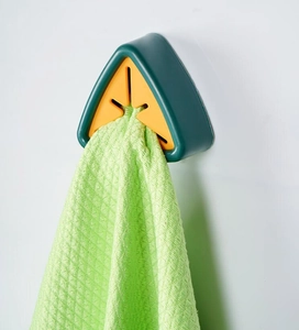 Macro shot of dark green triangular towel holder securing a green checkered cloth on wall