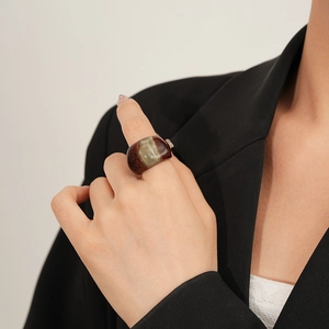 Detail of a minimalist resin ring featuring amber brown and grey green color blocking