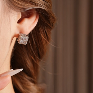 Gros plan sur un clou d'oreille carré en argent avec zircons et textures vintage