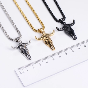 Bull head skull pendants in silver gold and black steel shown with measurement ruler