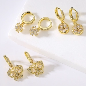 Three pairs of 18K gold plated zircon earrings with butterfly and floral designs on white texture
