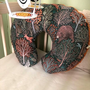 Close-up of forest animal patterned U-shaped nursing pillow cover on a wooden baby crib